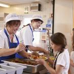 Dame servant le repas à une élève à la cantine