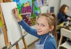Jeune fille en train de dessiner devant un chevalet