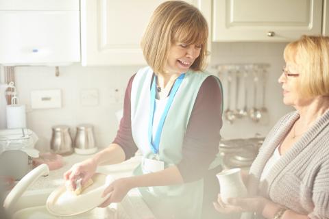 femme aidant un senior à faire la vaisselle. Aide ménagère.