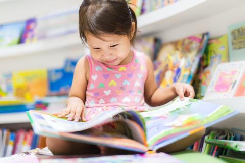 Petite fille lisant un livre dans une bibliothèque.