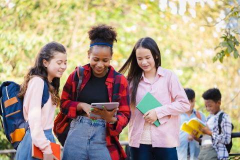 trois adolescentes consultent une tablette.