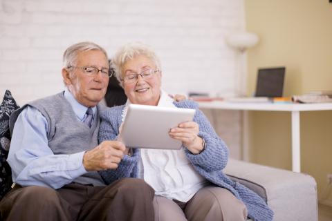 COUPLE DE SENIORS UTILISANT UNE TABLETTE NUMERIQUE