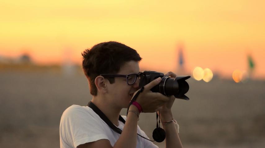 Jeune en train de prendre une photo au coucher du soleil