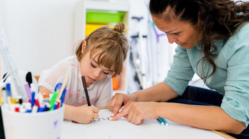 enfant dessinant devant une psychologue.