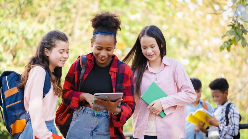 trois adolescentes consultent une tablette.
