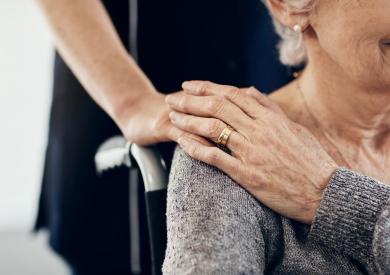 main jeune sur l'épaule d'une personne âgée